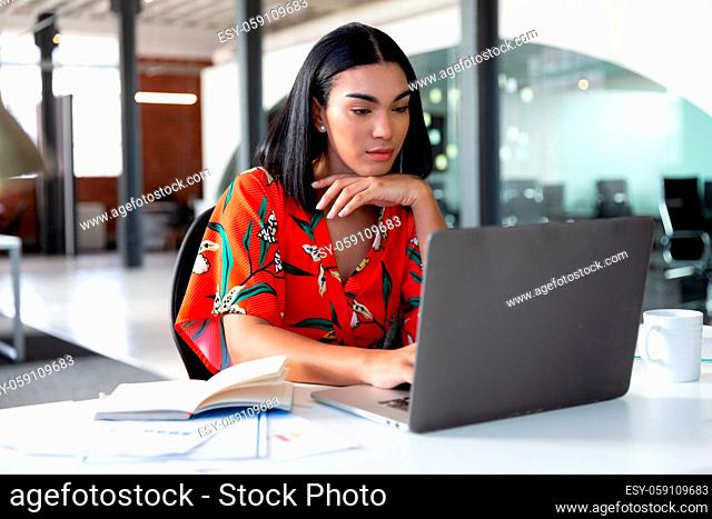 Portrait of mixed race businesswoman sitting in front of laptop working