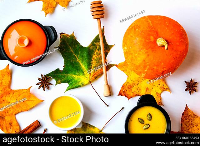 Autumn food. Pumpkin puree soup, leaves. Top view. Autumn harvest, pumpkins, leaves on grey as abstract background. View from above. Thanksgiving day