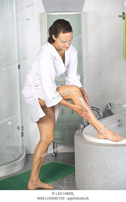young woman putting lotion onto her legs