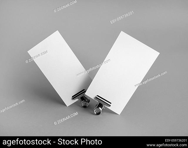 Photo of blank business cards and metal binder clips on gray background. Branding ID template