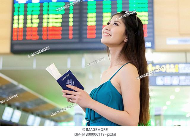 Young woman holding passport and airplane ticket with smile