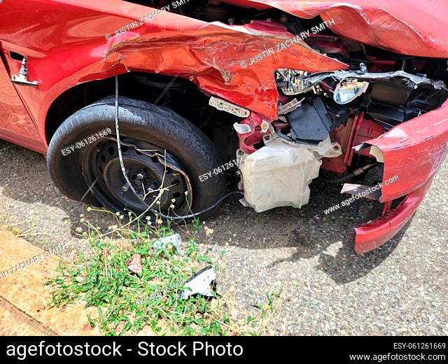 damaged and broken red car or automobile on road or street