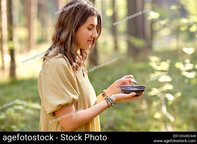 woman or witch performing magic ritual in forest