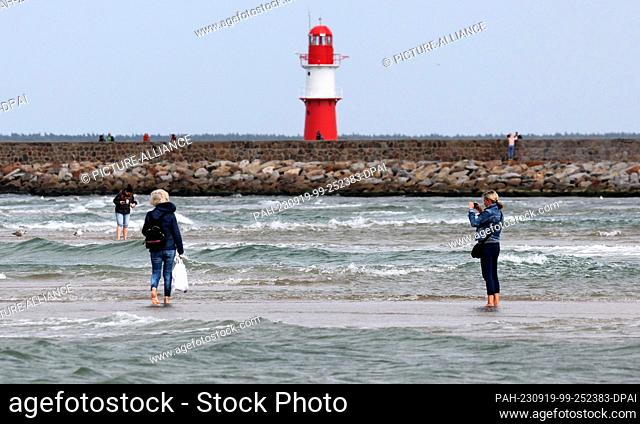 19 September 2023, Mecklenburg-Western Pomerania, Warnemünde: Walkers are out on the Baltic Sea beach and can walk on a sandbank far towards the sea because...