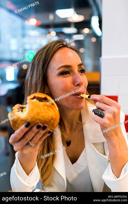 Beautiful female professional having burger while looking away