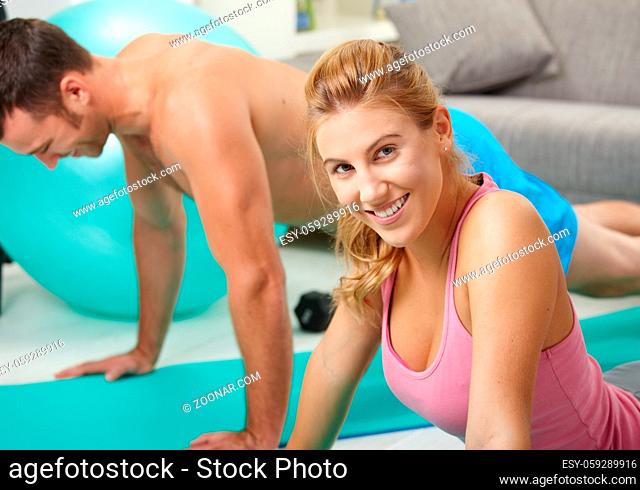 Young couple doing push up exercise at home in living room
