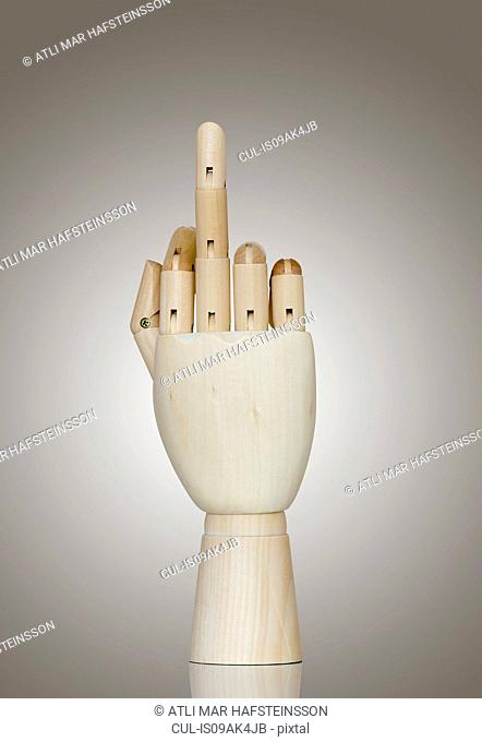 Wooden hand making rude gesture with middle finger