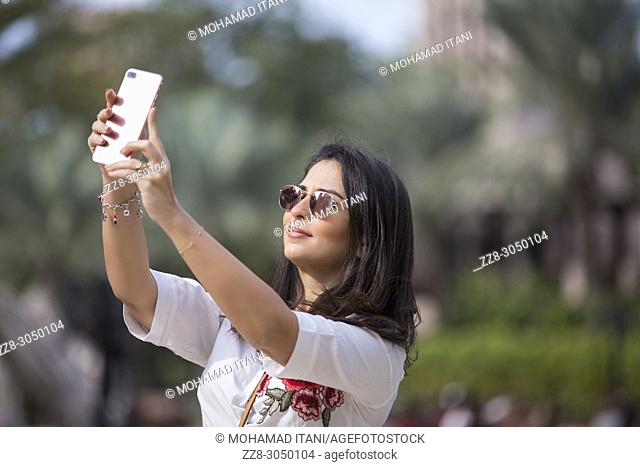 Beautiful woman taking a selfie picture with a mobile phone at Madinat Jumeirah Dubai UAE