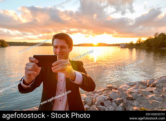 Portrait of young handsome Scandinavian businessman in suit at beautiful view of the shore