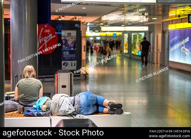 14 July 2022, Lower Saxony, Hanover: A traveler sleeps on a bench at Hannover Airport. In Lower Saxony, the summer vacations run from July 14 to August 24, 2022
