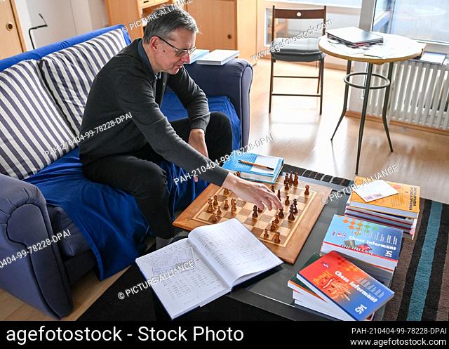 01 April 2021, Berlin: The chess player Ludger Heiermann plays correspondence chess by post in his apartment and is surrounded by his notes and chess books