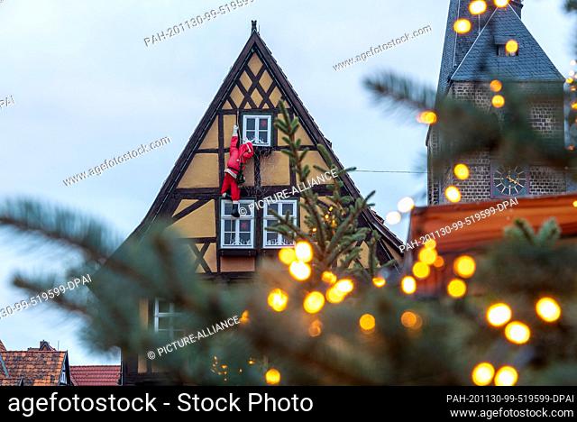 29 November 2020, Saxony-Anhalt, Quedlinburg: Santa Claus"" climbs into a historic half-timbered house on the Quedlinburg market square