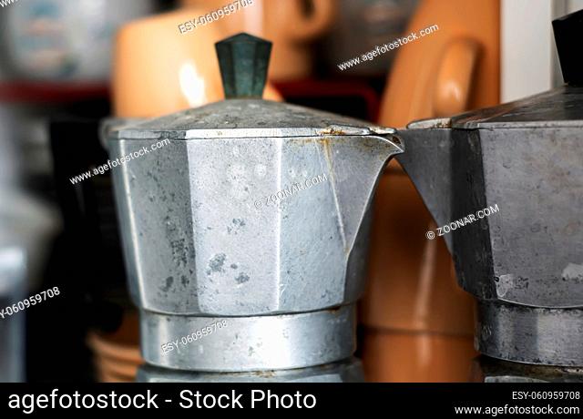 Close-up view of an old rusty coffee pot inside a pantry. Scratches and signs of wear near the spout. Design object. Italian culture