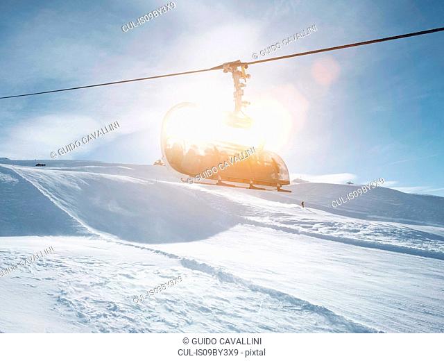 Sunlit ski lift in snow covered mountain landscape, Alpe Ciamporino, Piemonte, Italy