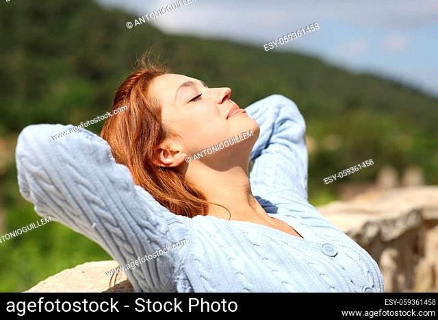 Satisfied woman resting in a sunny day in a balcony