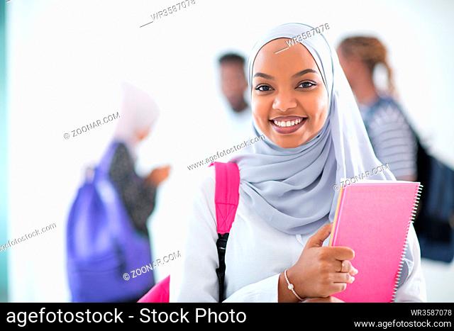 african female student with group of friends in background wearing traditional Islamic hijab clothes