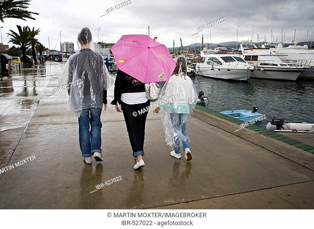 Woman with umbrella in the rain with children at the harbour, Ibiza, Baleares, Spain