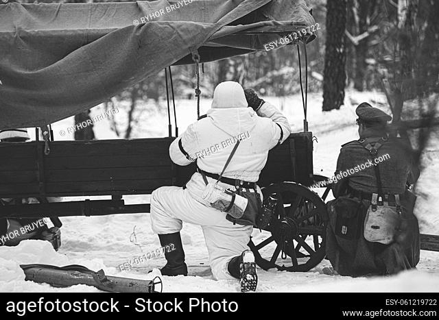 Hidden Re-enactor Dressed As German Wehrmacht Infantry Soldier In World War II Soldiers Sitting In Ambush Near Peasant Cart In Winter Forest And Looking At Old...