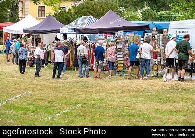 26 July 2020, Saxony, Meißen: On the day of the open baroque palace Proschwitz, visitors stand in the garden of the palace and look at the products on offer at...
