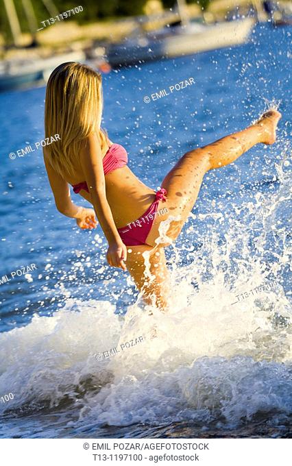 Kicking water young woman on the beach