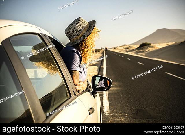 Tourist enjoy sun and outdoors outside the window of the car during a break. Vehicle parking on the side of the road and woman people admiring landscape