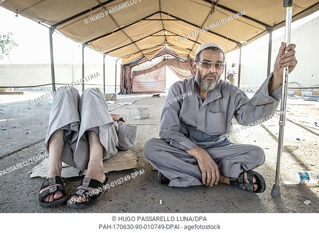 Displaced Iraqi old men take a rest after fleeing the heavy fight between Iraqi forces and the Islamic State in the old city of Mosul while they wait for a...