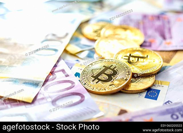 Euro banknotes and bitcoins. The golden cryptocurrency