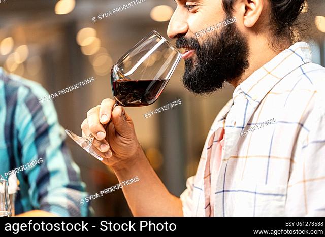 man with glass drinking red wine at restaurant