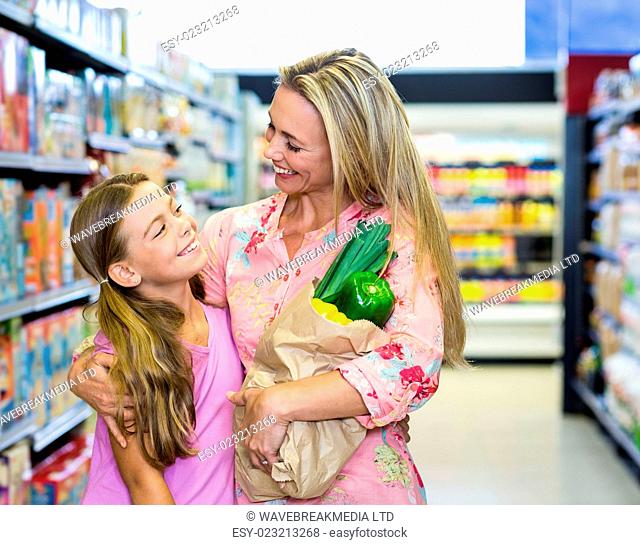 Smiling mother and daughter with grocery bag at the supermarket