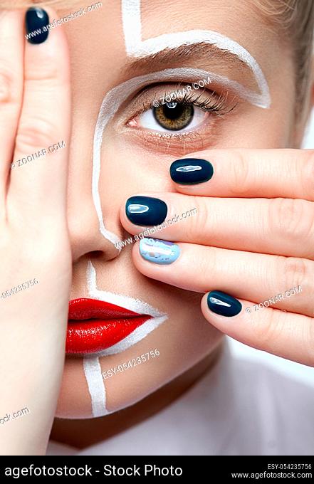 Beauty fashion portrait of a young woman on gray background. Female with an unusual creative makeup face painting. Girl with hands near face