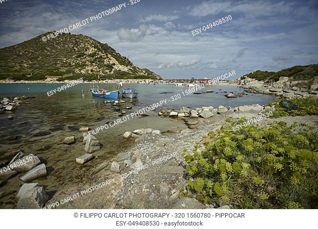 Beautiful view of Punta Molentis, a natural beach on the southern coast of Sardinia with a couple of small fishing boats moored on the shore