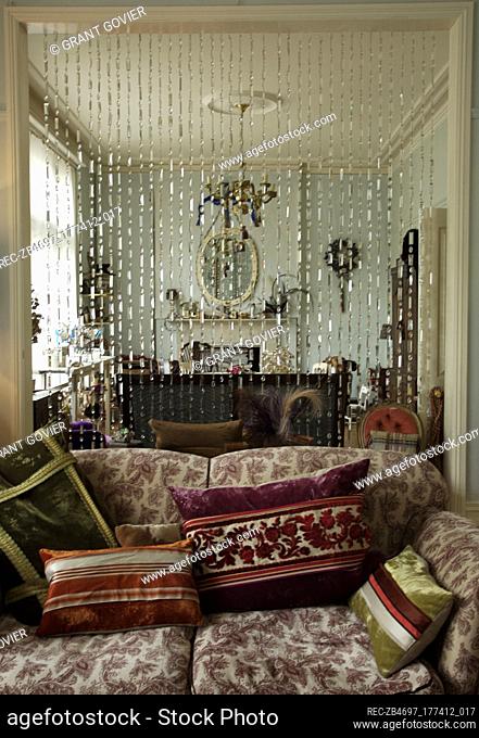 Beaded curtain behind patterned sofa in sitting room