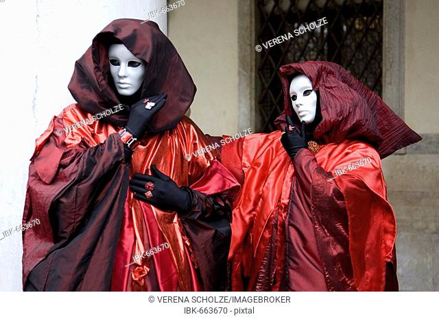 Two people wearing red-and-black costumes, hooded cloaks and masks, Carnevale di Venezia, Carneval in Venice, Italy