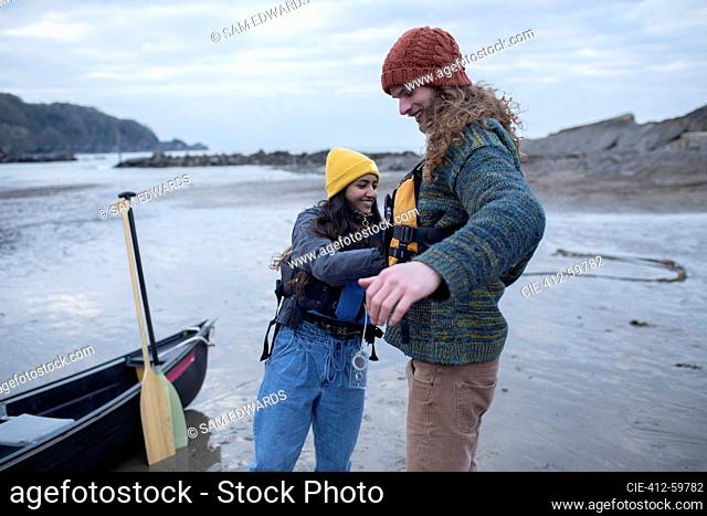 Young couple preparing for canoeing on ocean beach