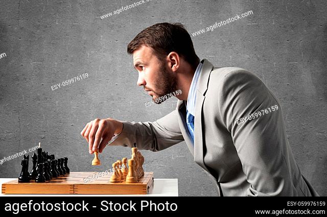 Concentrated businessman playing chess game. Successful management and leadership concept. Confident young man in business suit sitting at desk with chess