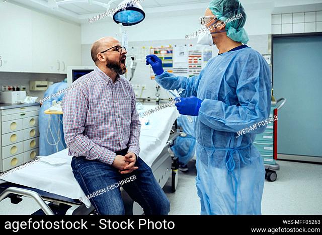Doctor in hospital taking a swab from patient's mouth