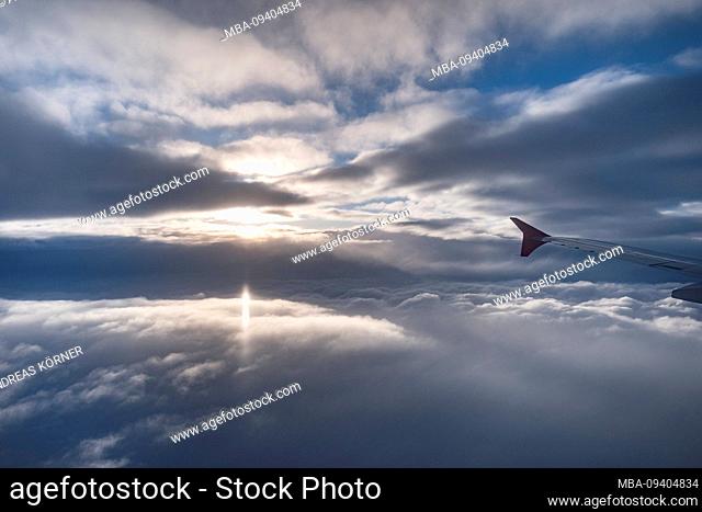 View from the window of an airplane on closed cloud cover at sunset