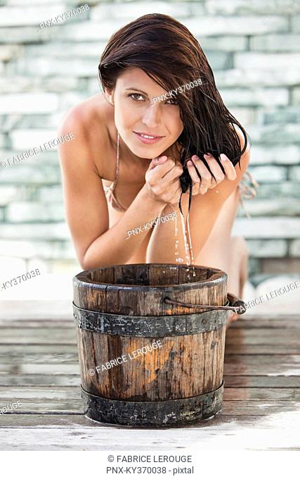 Portrait of a woman washing hair into a bucket