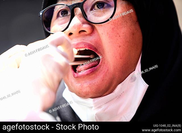 A health worker, wearing protective suit, performs a swab test mass on a woman during in Bandung, West Java, Indonesia, May 10, 2020