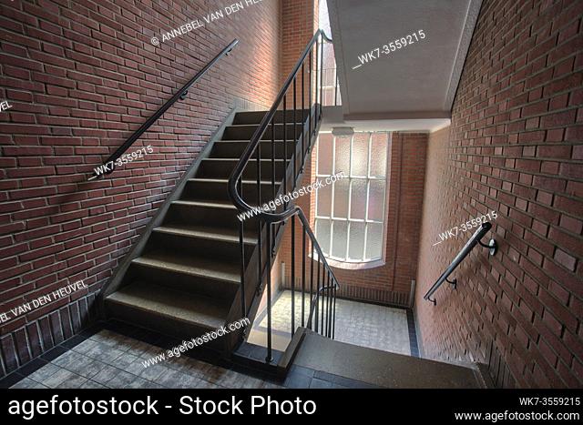 Stairwell in appartment building with brick wall, staircase antique old style complex with tall windows flat building