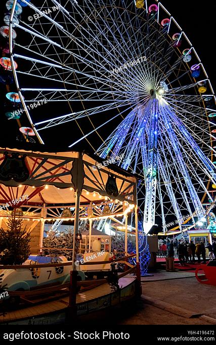 Glistening holiday market beneath a radiant Ferris wheel in Le Barcarés, a festive night scene illuminated by Christmas lights