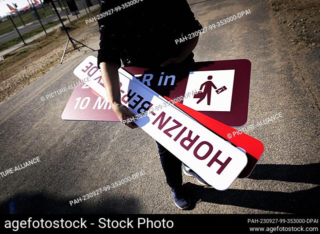 27 September 2023, Brandenburg, Schönefeld: A woman holds a sign reading Horizn-Ber-City.de before a photo opportunity at an event to introduce the site of Part...