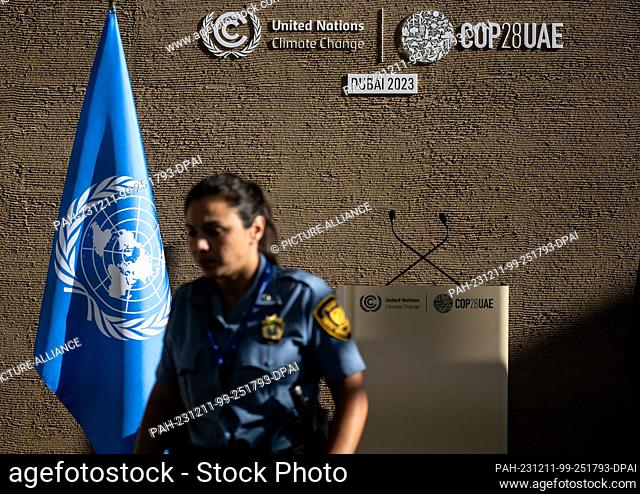 11 December 2023, United Arab Emirates, Dubai: A security guard stands in front of a wall with the words ""United Nations Climate Change | COP28UAE""