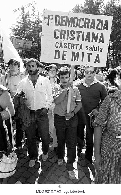 People attending the 7th National Friendship Day. A young fan holds a sign exalting the Honourable Ciriaco De Mita. Fiuggi, September 1983