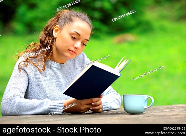 Relaxed woman in a park or camping reading a book