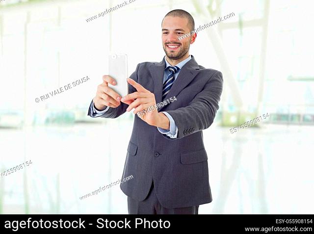 businessman in suit and tie taking selfie photo with mobile phone camera posing happy and successful at the office