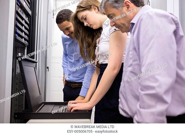 Three technicians looking at laptop in data center