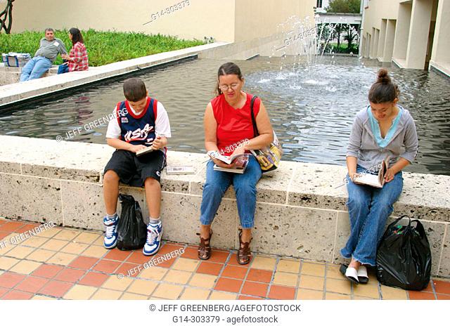 Family reading near fountain by Public Library. Miami-Dade Cultural Center Plaza. Miami. Florida. USA