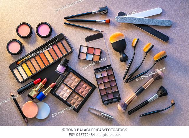 Cosmetics makeup lipstick eye shadows arrangement on glitter silver table