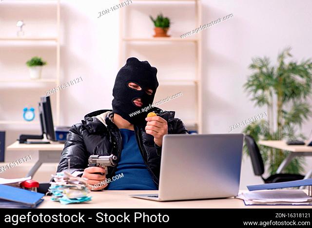 Young male burglar in the office room
